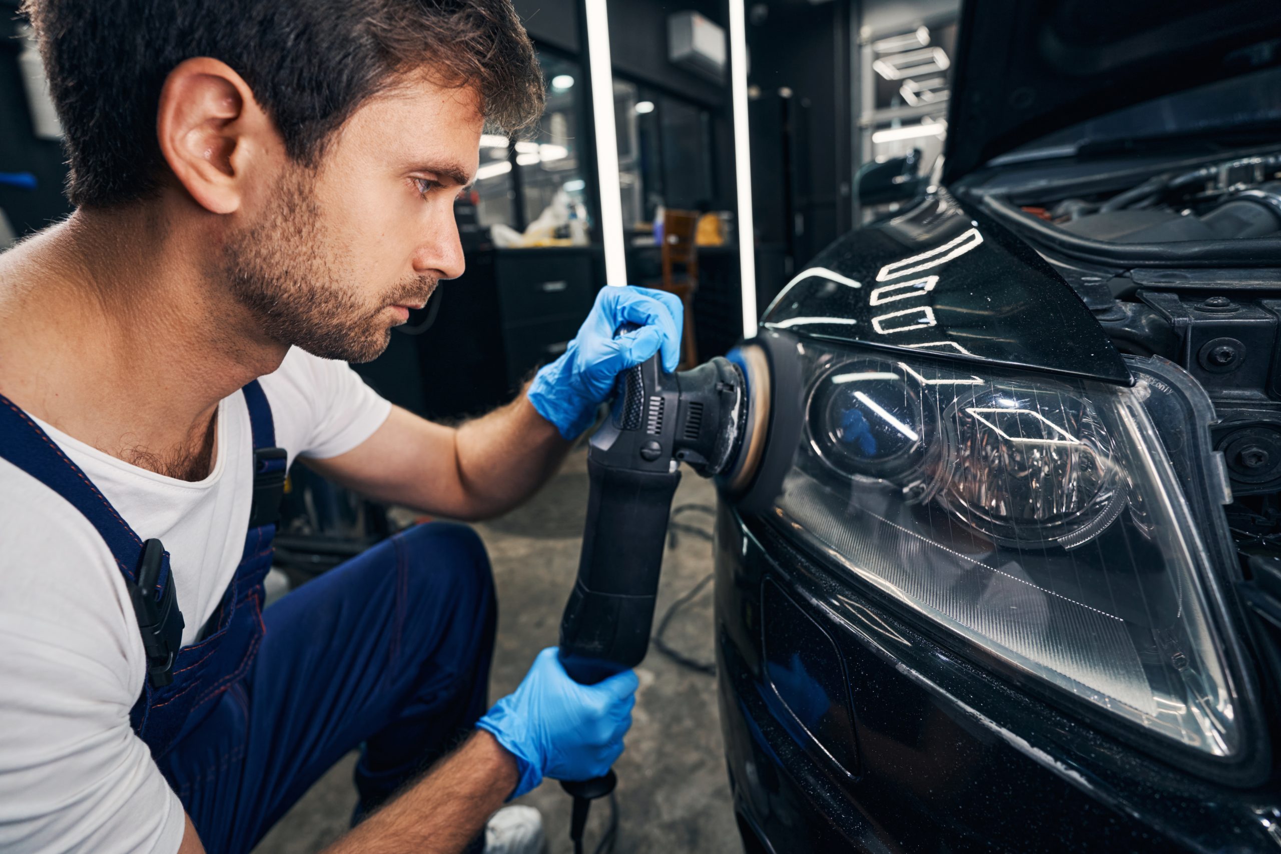 A technician cleaning a car's headlights during the detailing process