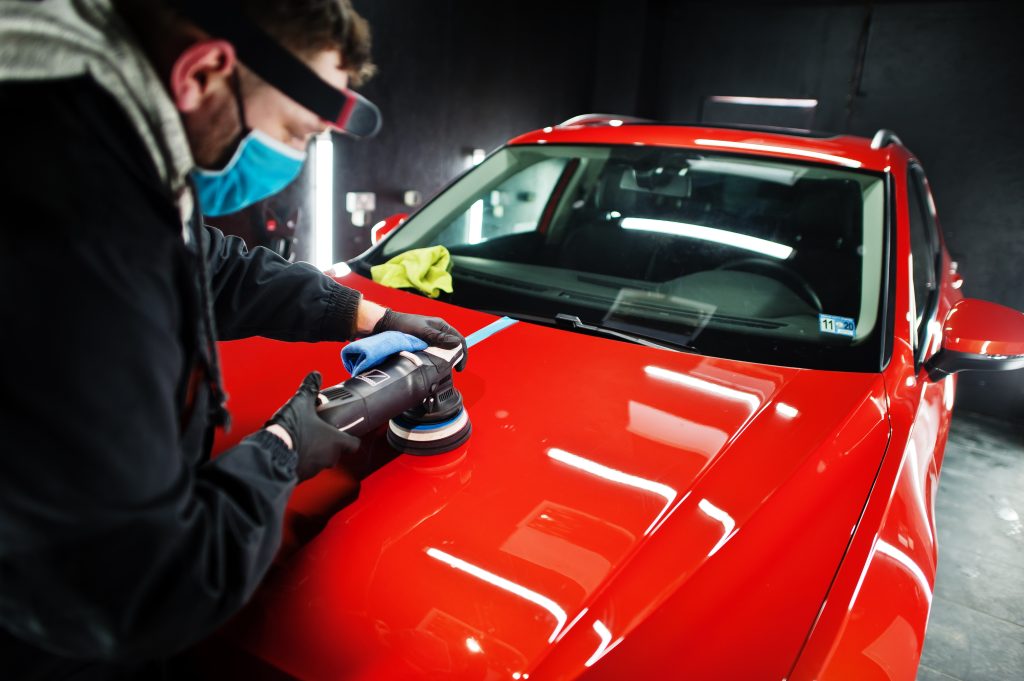A professional doing a ceramic coating on a red car