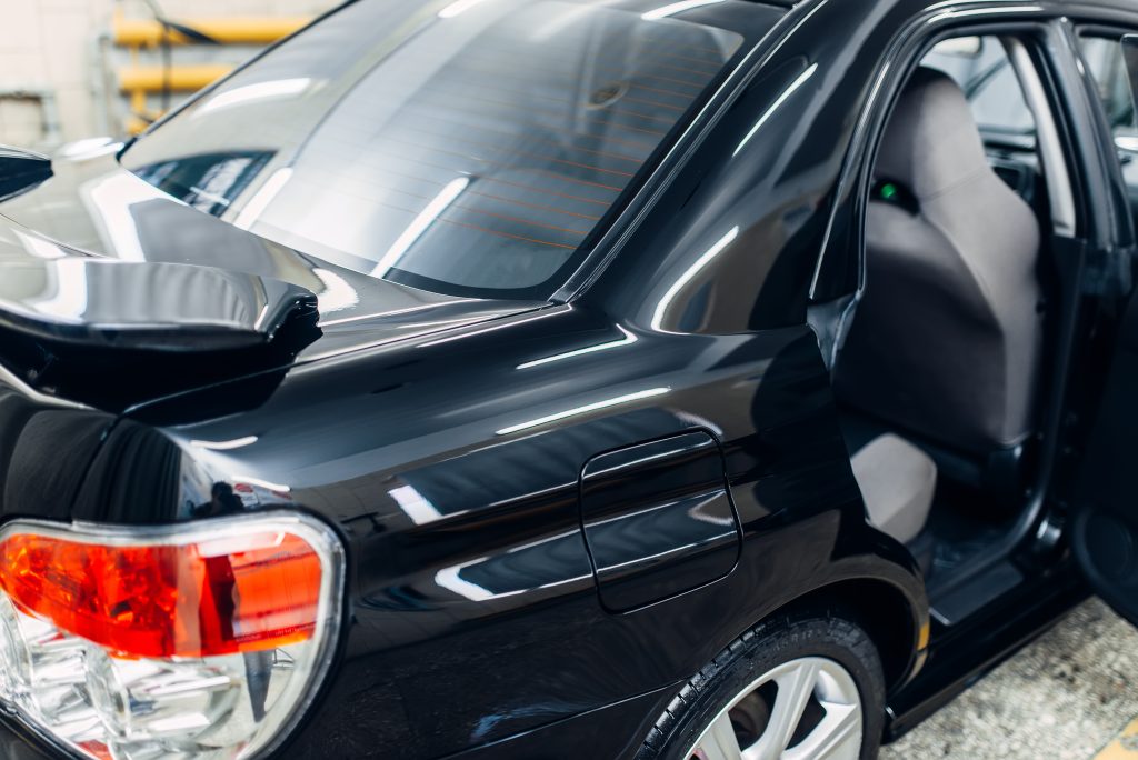 A close-up of a freshly waxed car reflecting the surroundings with a brilliant shine.